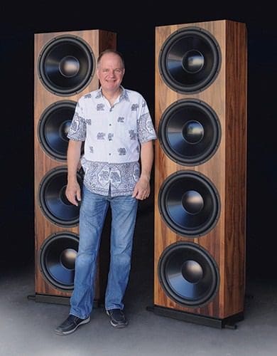 A man standing in front of two large speakers.