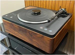 A record player sitting on top of some other records.